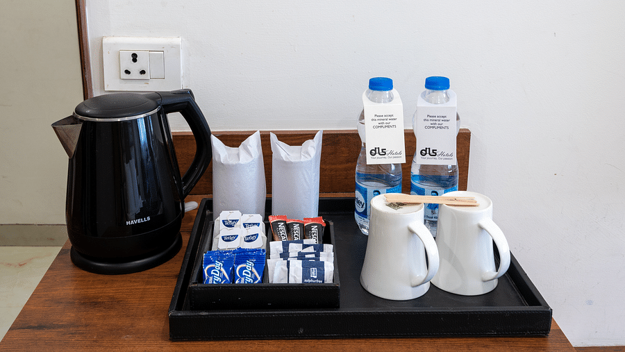 Tea and coffee maker with milk powder, tea and coffee sachets, and two mugs placed on a table at DLS The Classio